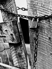 An old wooden gate with an old lock and thin chain