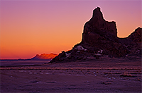 Arizona sunset with a lone peak of a mountain in the distance. Red and yellow colors
