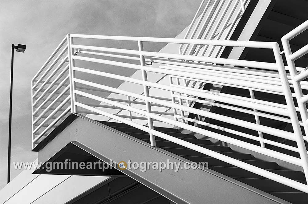 black and white image of metal stairs leading up to a lamp on the corner