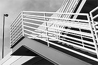 black and white image of metal stairs leading up to a lamp on the corner