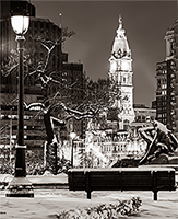 A picture of a bench next to a lamp pole in Philadelphia at night with snow