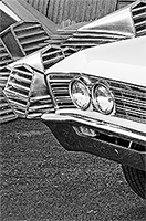A partial front end of an El Camino in front of a pile of metal vents for a roof
